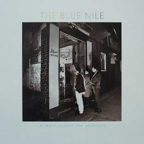 Allmusic album Review : The Blue Niles debut album has a rather fascinating genesis. Scotlands Linn Electronics wanted a demo track to demonstrate the fidelity and versatility of their new recording console and tapped a struggling local trio, the Blue Nile, to provide it. Their effort was a deliberately disjunctive song called "A Walk Across the Rooftops." To demonstrate the recording equipments dynamic range and clarity, the song was arranged most peculiarly, with vocals, guitar, bass, keyboards, drums, and full string and horn sections all appearing, but never at the same time. Linn liked the song so much that they formed a record label and bankrolled the recording of this full album. The seven lengthy tracks on A Walk Across the Rooftops all follow the model of the opener, with Paul Buchanans rich voice at the center of near-symphonic arrangements that manage to sound lush and incredibly austere at the same time. The tempos are deadly slow, with the most upbeat track, "Tinseltown in the Rain," barely rising above a graceful saunter, and the inventive arrangements make extensive use of empty space. This was a popular album for demonstrating the lack of hiss and background noise in the then-new compact disc medium, but A Walk Across the Rooftops works even better as a piece of music than as a stereo demonstration record.